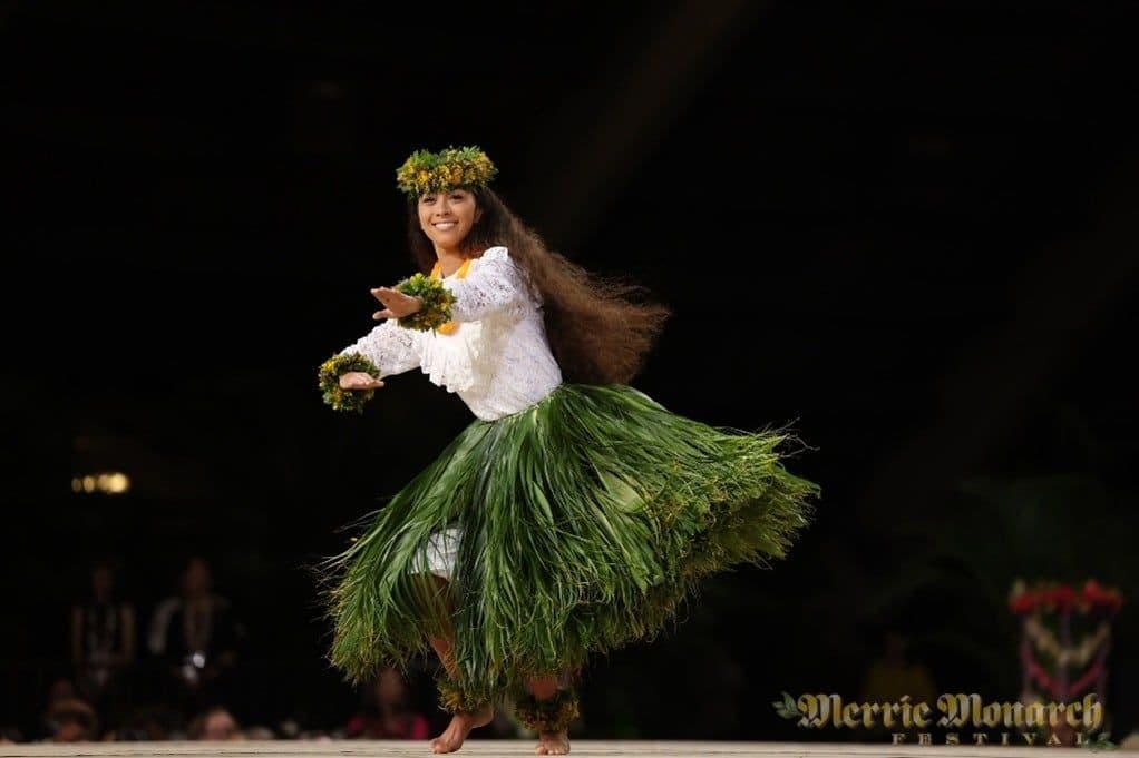 Woman dancing hula in grass skirt.