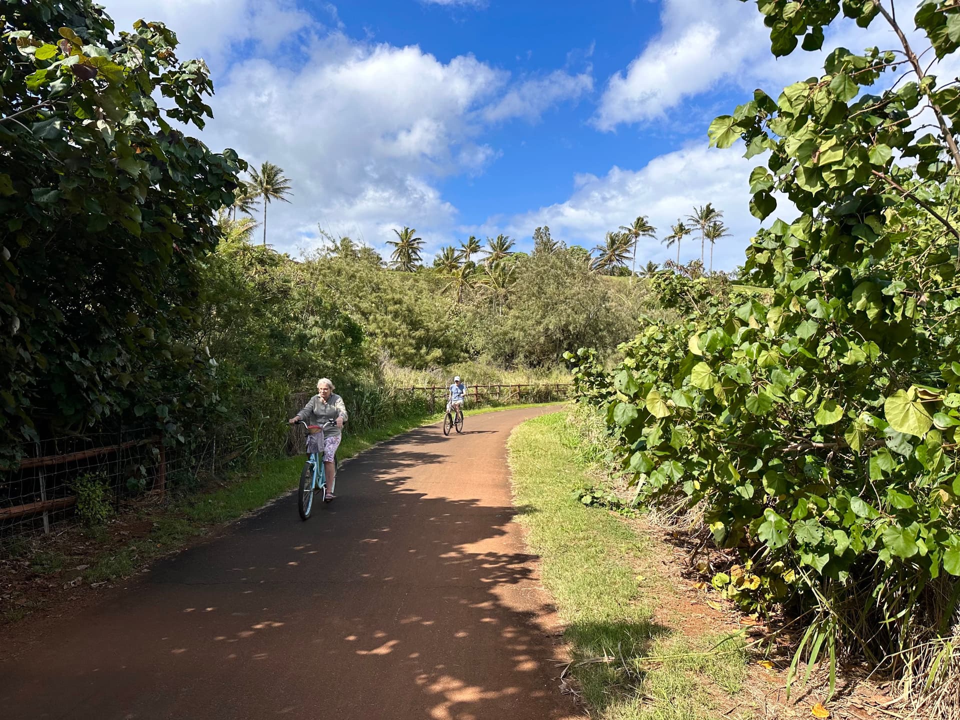 A woman and child riding bikes down a dirt road on Kapaa bike path in Kauai, Hawaii.