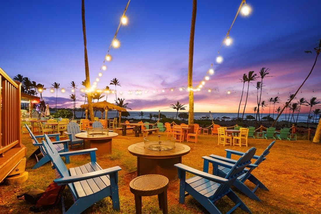 A beach bar on Kauai lit up by string lights at sunset.