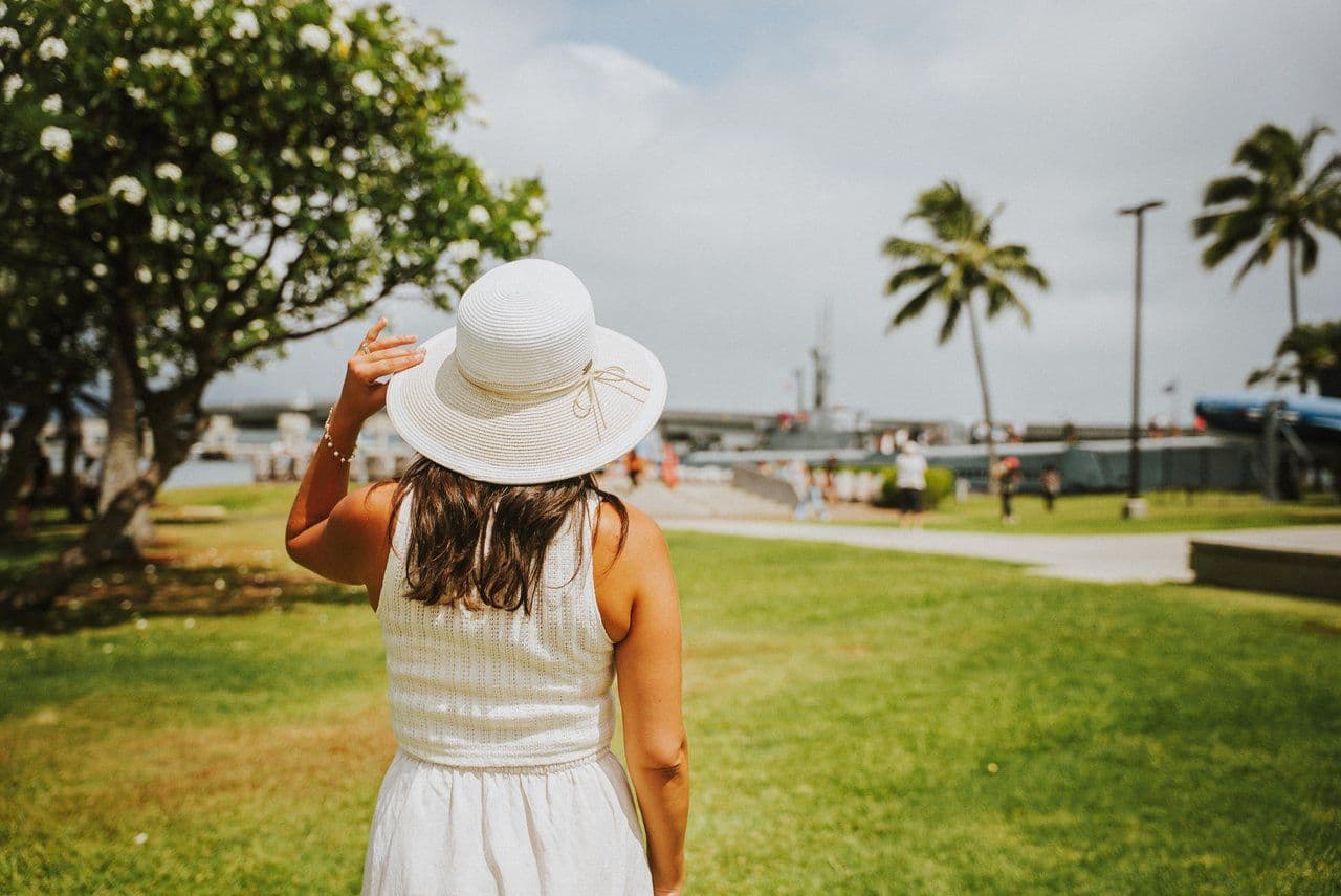 a woman standing in front of pearl harbor visitor center wearing all white