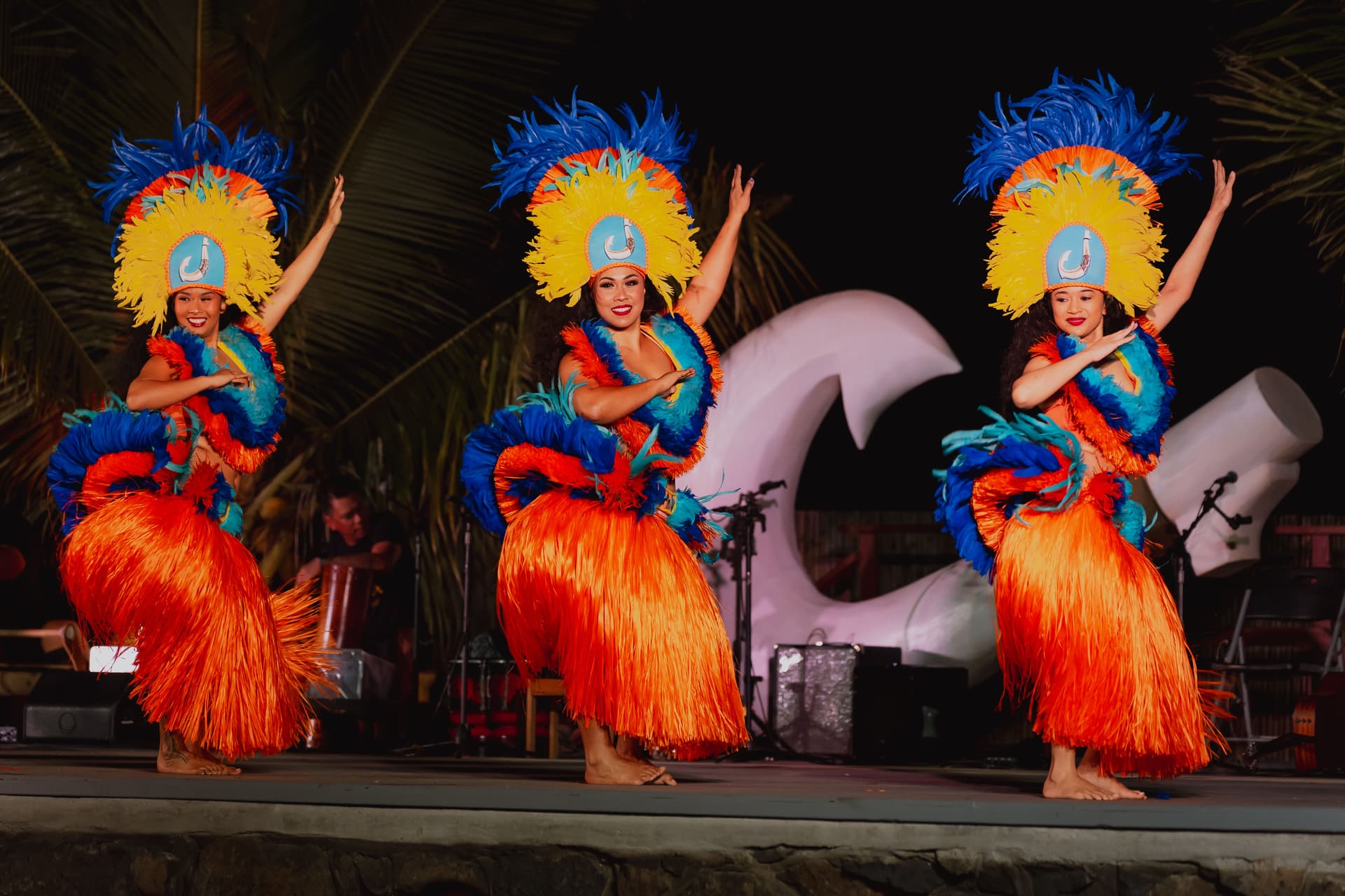 Women in colorful garb dance on stage at luau