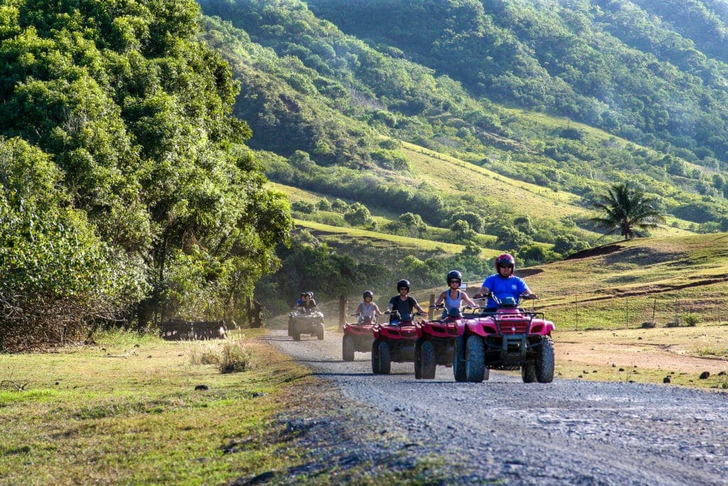 A tour group travels on ATVs on the Kualoa Ranch to see movie filming sites in Oahu, Hawaii