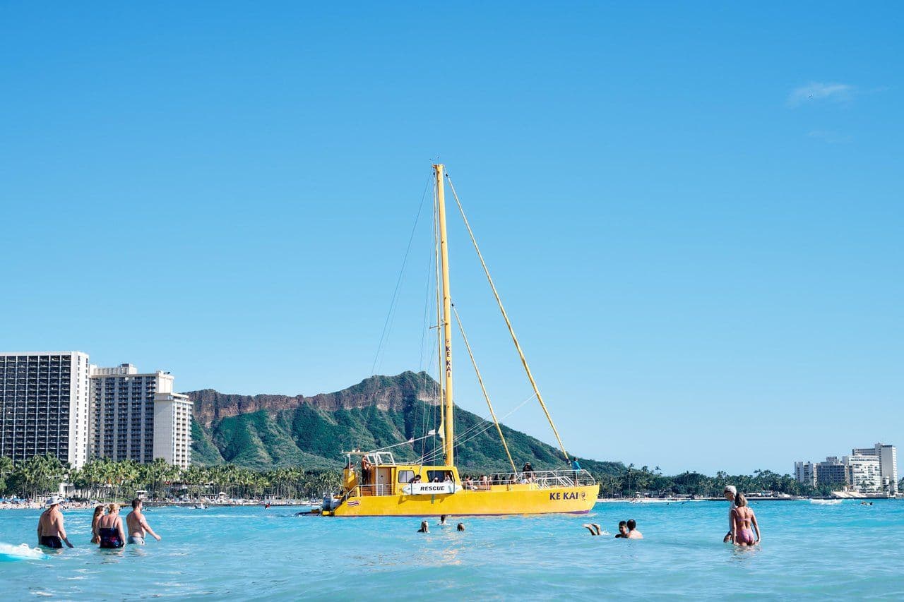Waikiki beach with lots of people and diamond head crater in the distance on Oahu Hawaii.