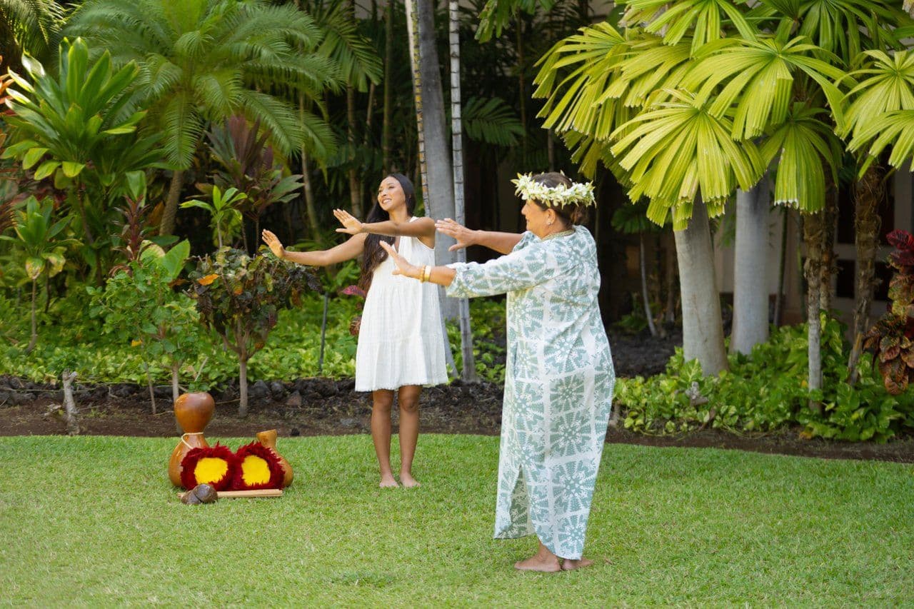 Two women doing hula on the grass