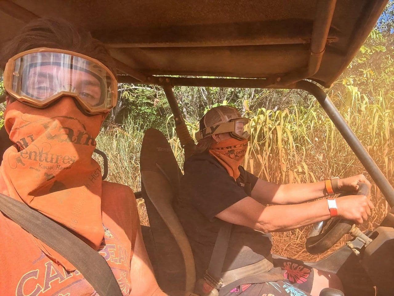 people in goggles in the dust riding in ATV