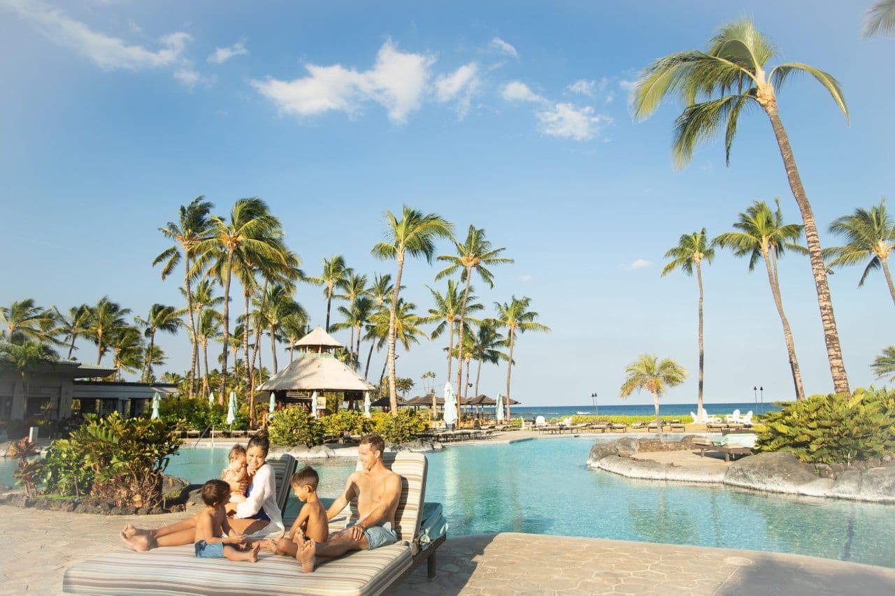 A family of four relaxing by an oceanfront pool