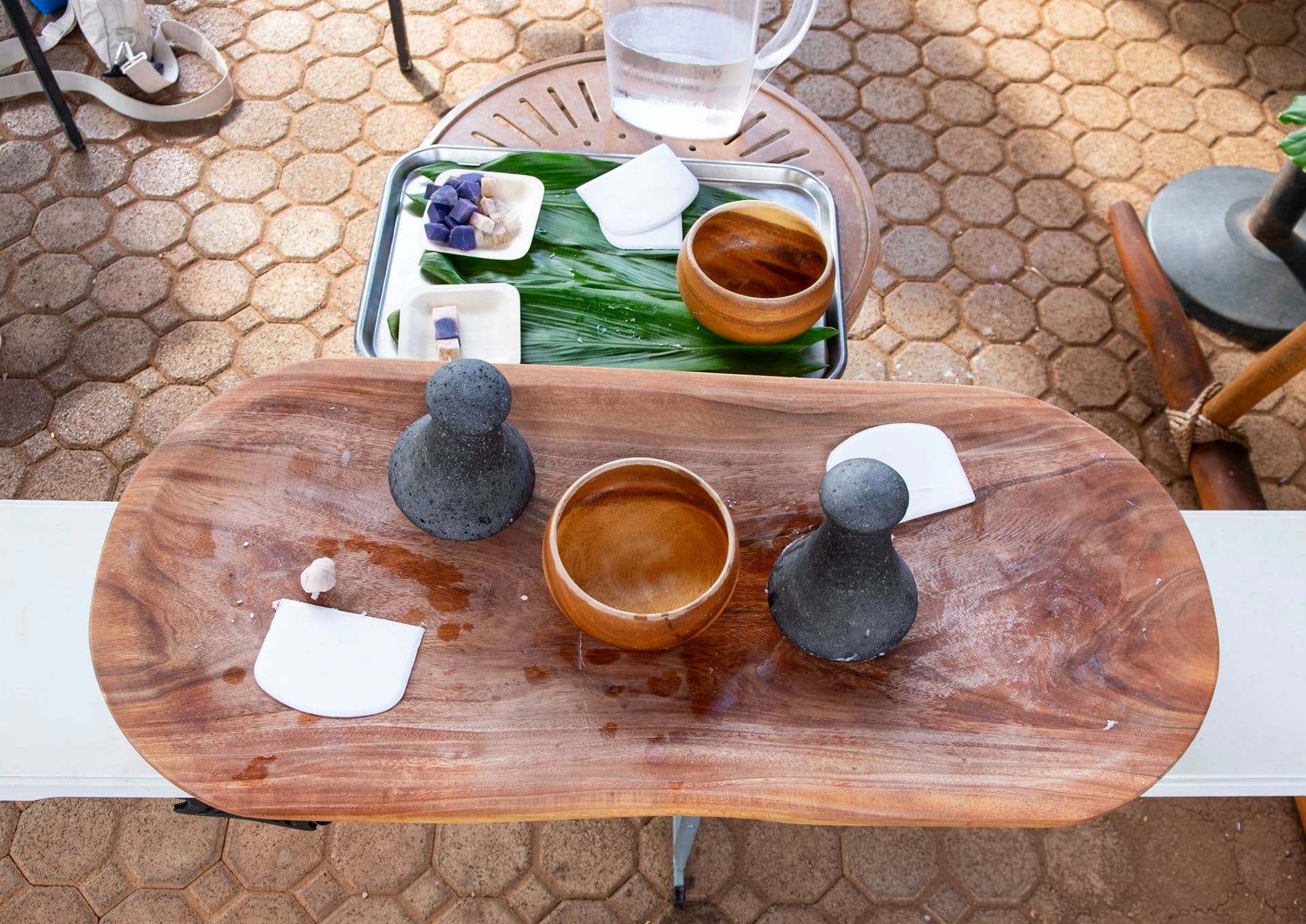 A traditional poi pounding board with poi pounders and water.