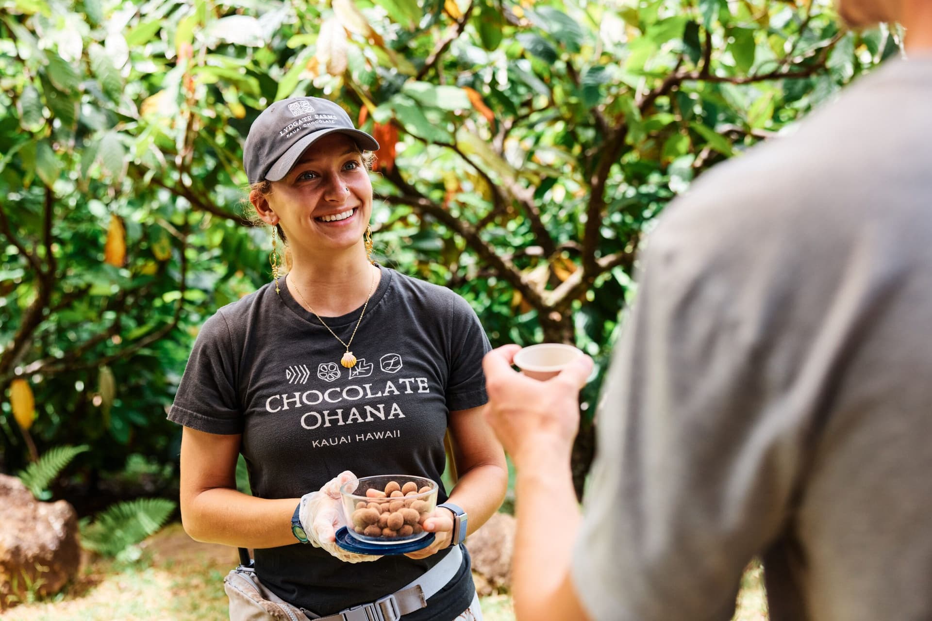 woman holding chocolate covered macadamia nuts on a cacao farm