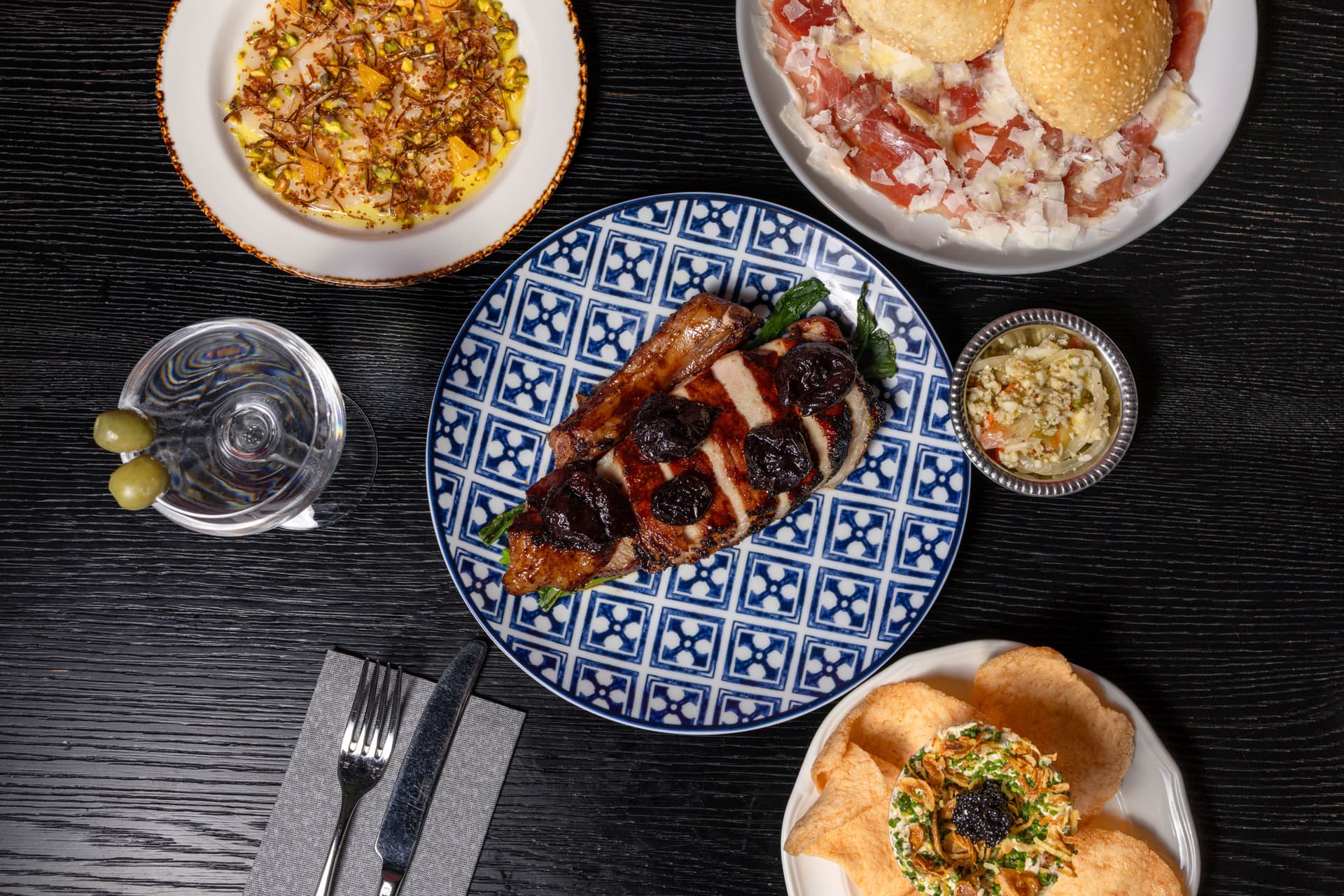 Food and cocktails on a black table.