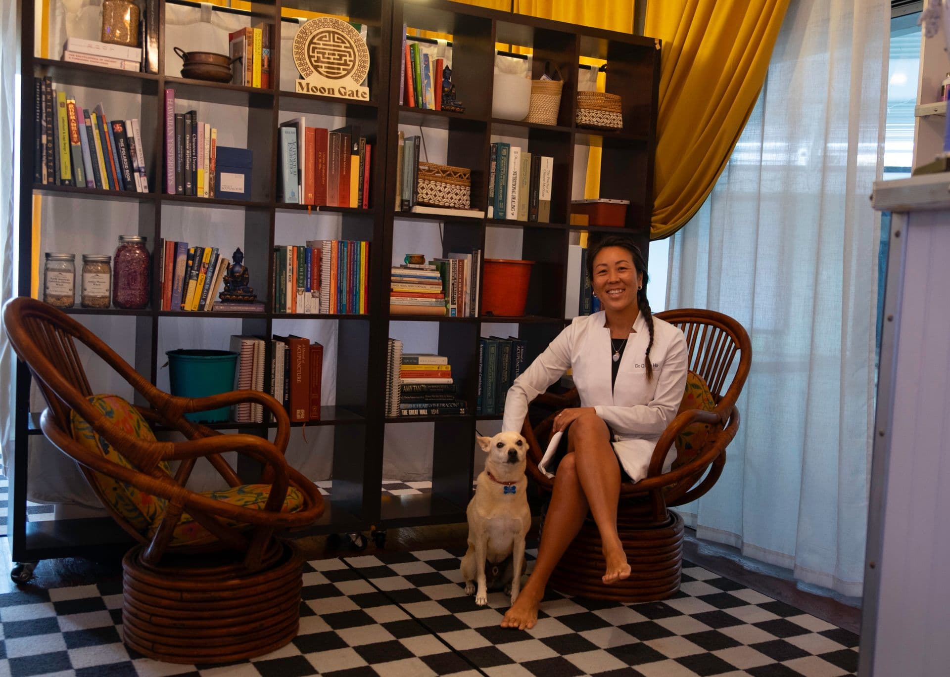 doctor of acupuncture with her dog in front of bookshelves