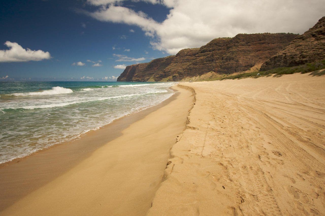 big wide sandy beach with mountains in the background in kauai