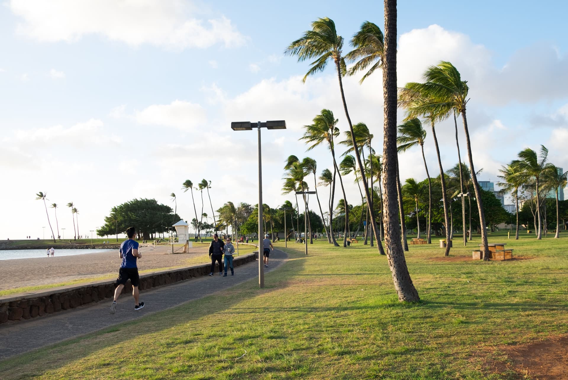 People jogging down a coastal walking path at ala moana beach park in honolulu on oahu.