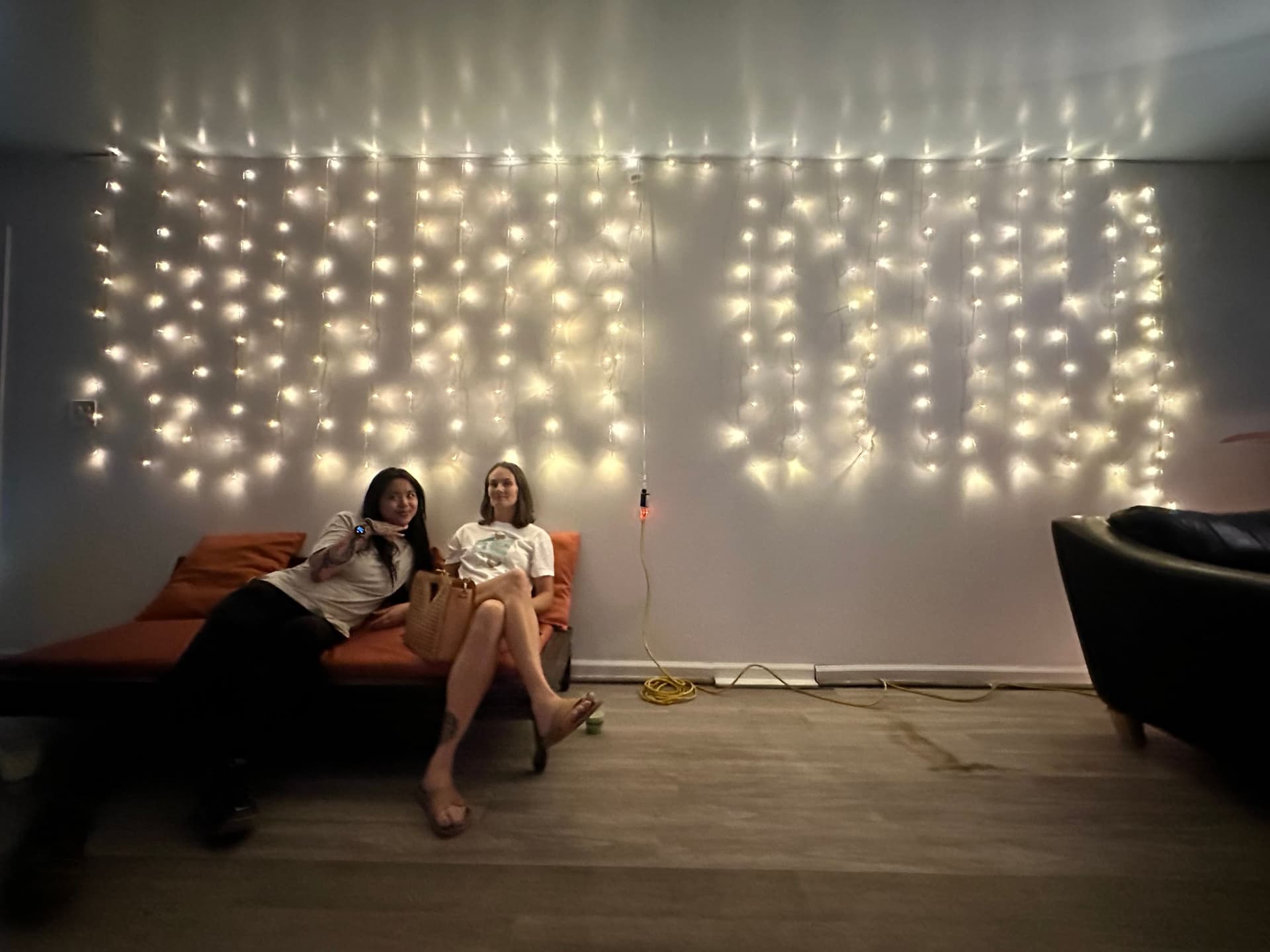 two women sitting on a couch with christmas lights