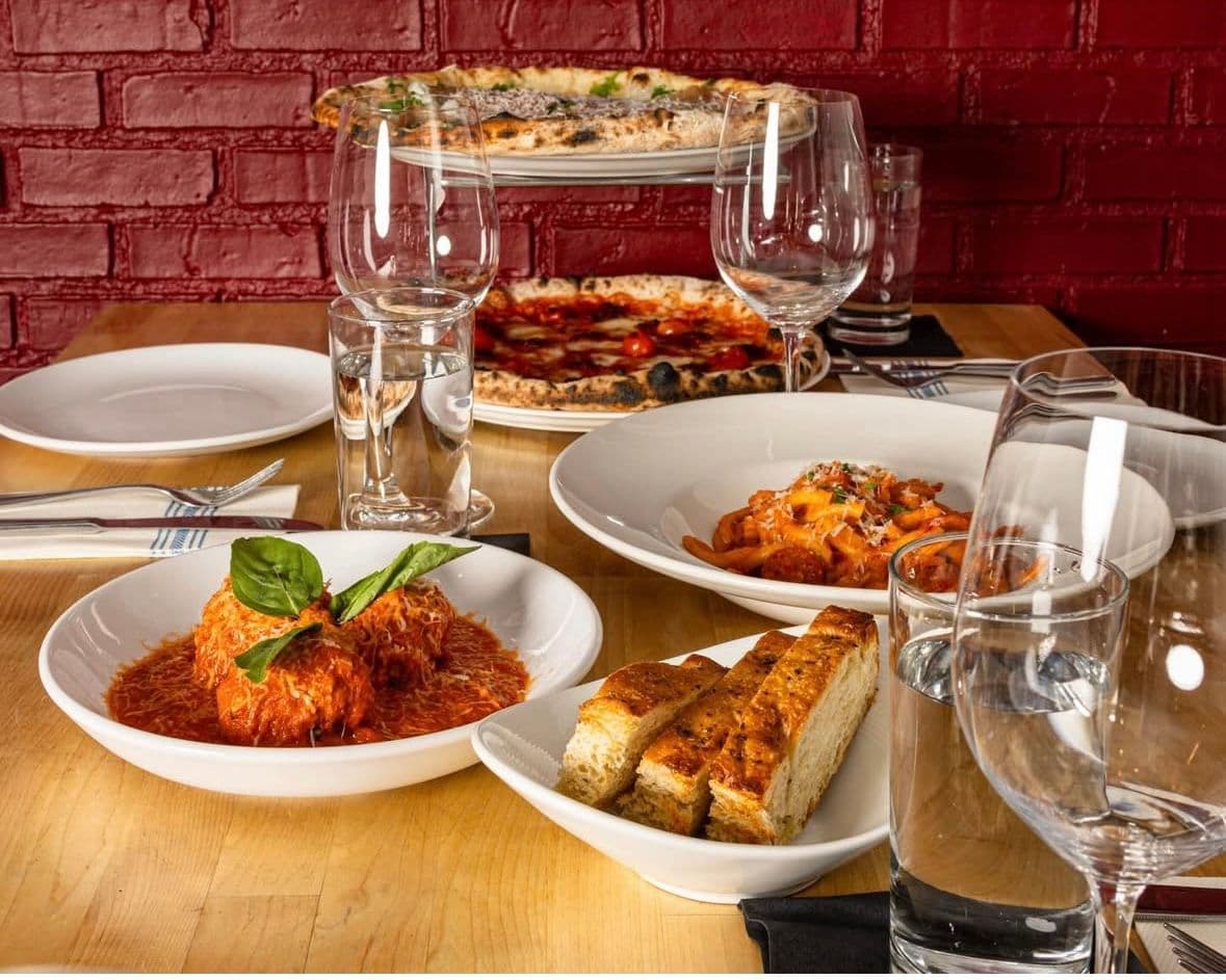 Italian dishes on a table. Pizza, pasta, meatballs.
