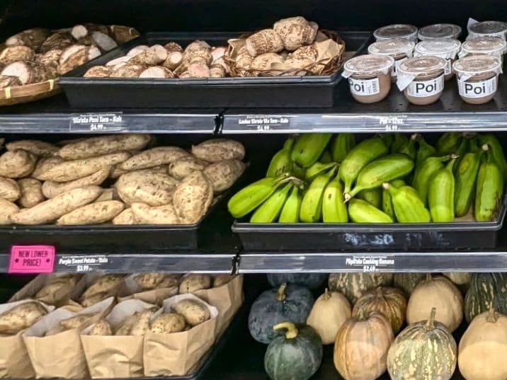 grocery shelves with sweet potatoes, bananas, squash and poi.