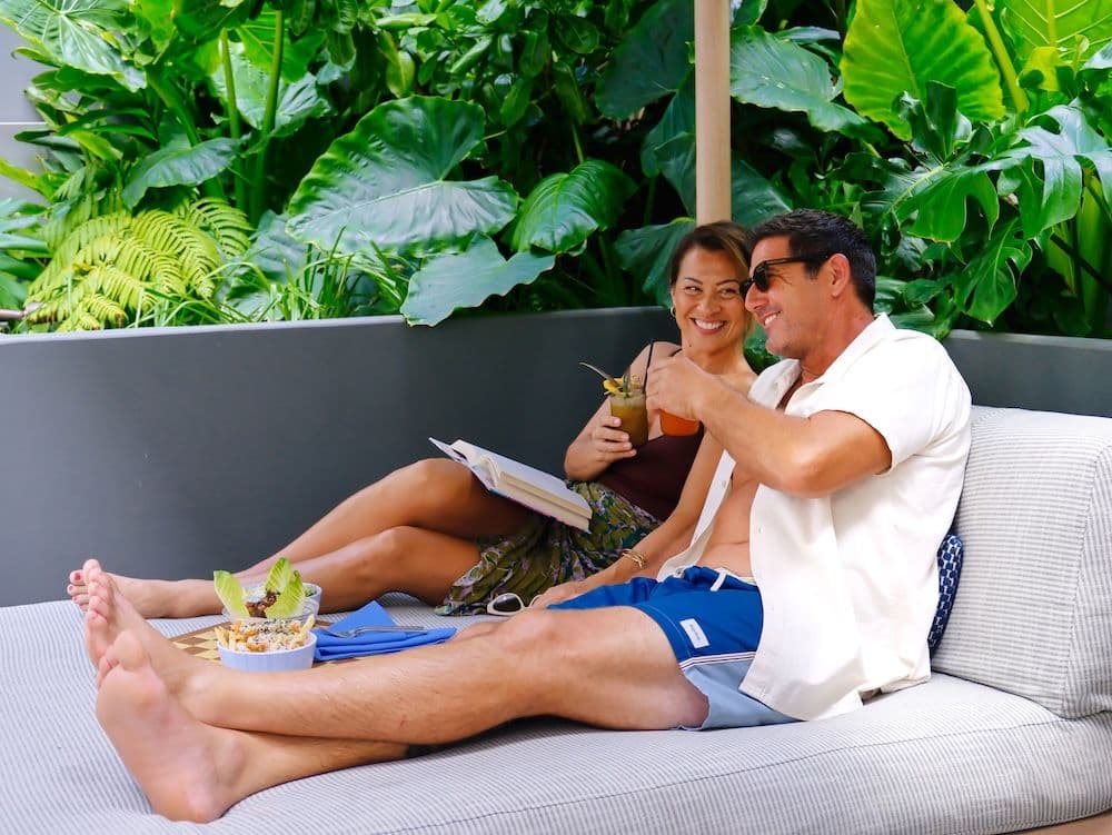 A couple toasting cocktails in a pool cabana in Hawaii.