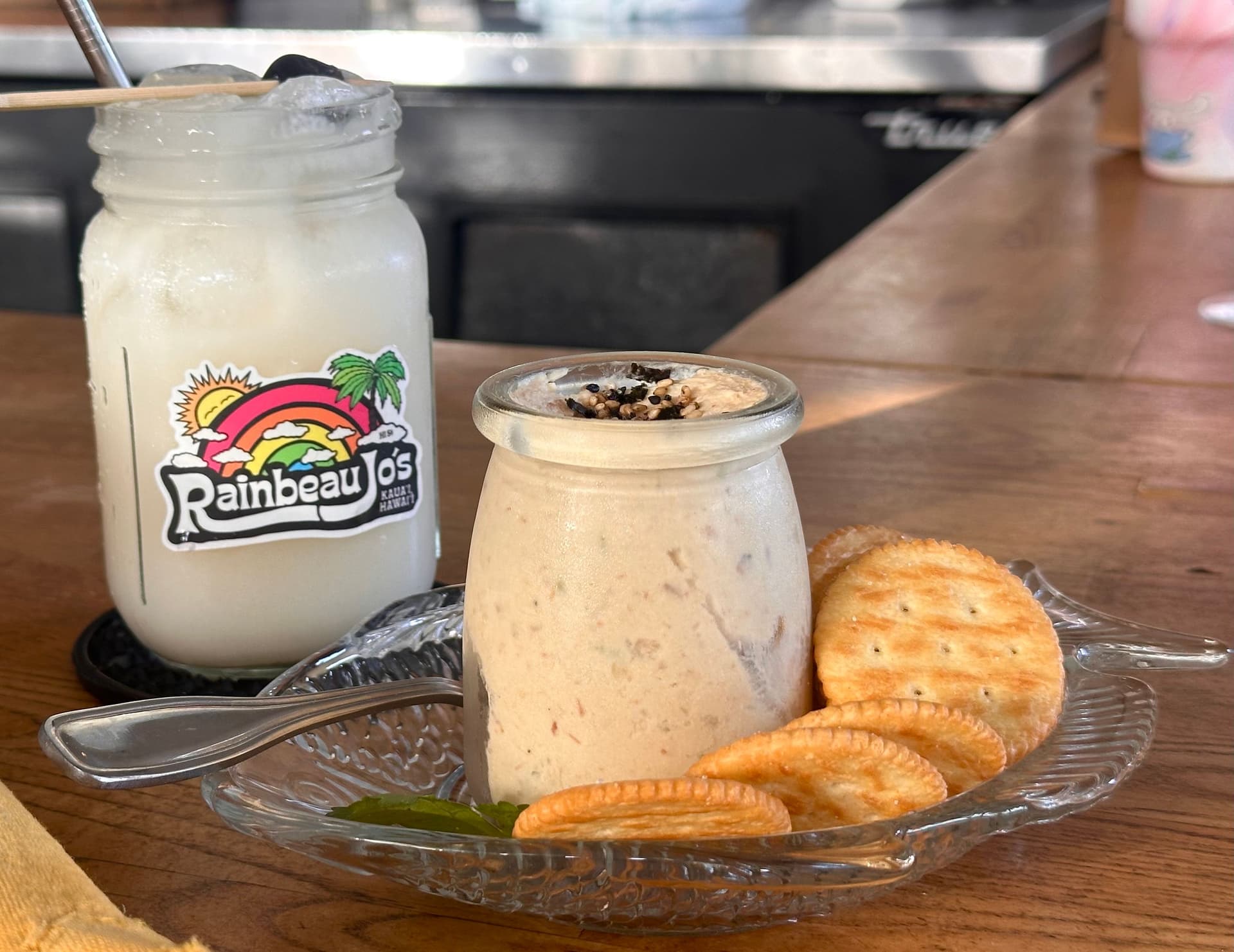 White coconut milk cocktail and jar of smoked fish spread with ritz crackers at Fish Bar Deli in Kauai.