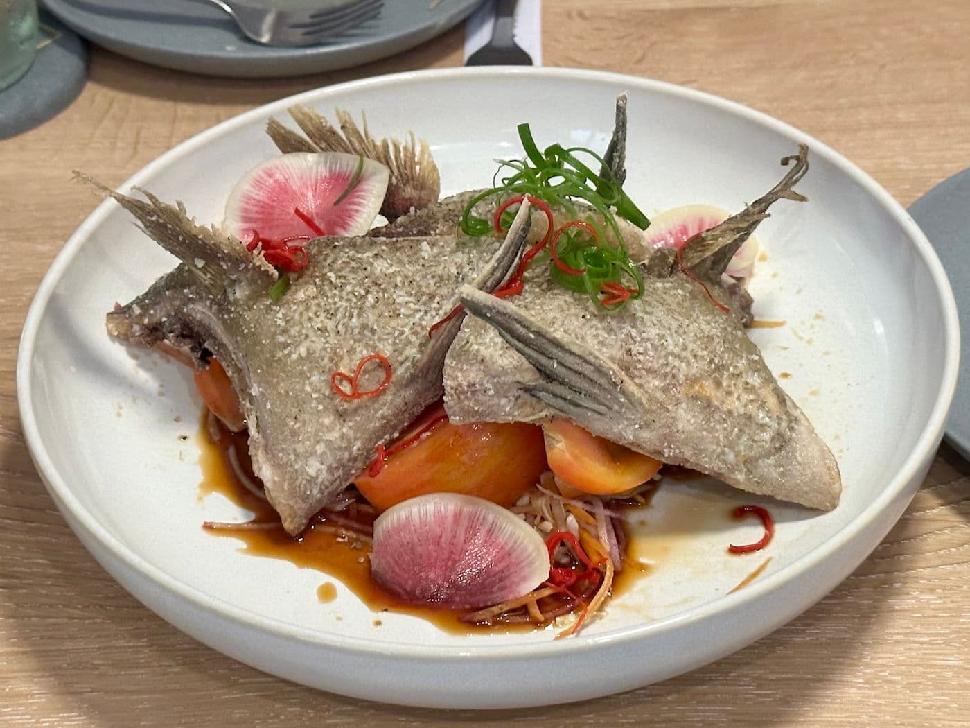 Crispy fish collars with tomatoes and radishes at Aurum Maui restaurant.