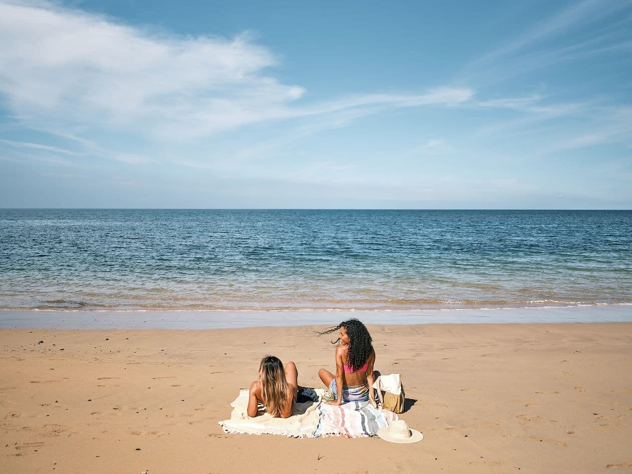 two girls sunbathing on the beach in hawaii.