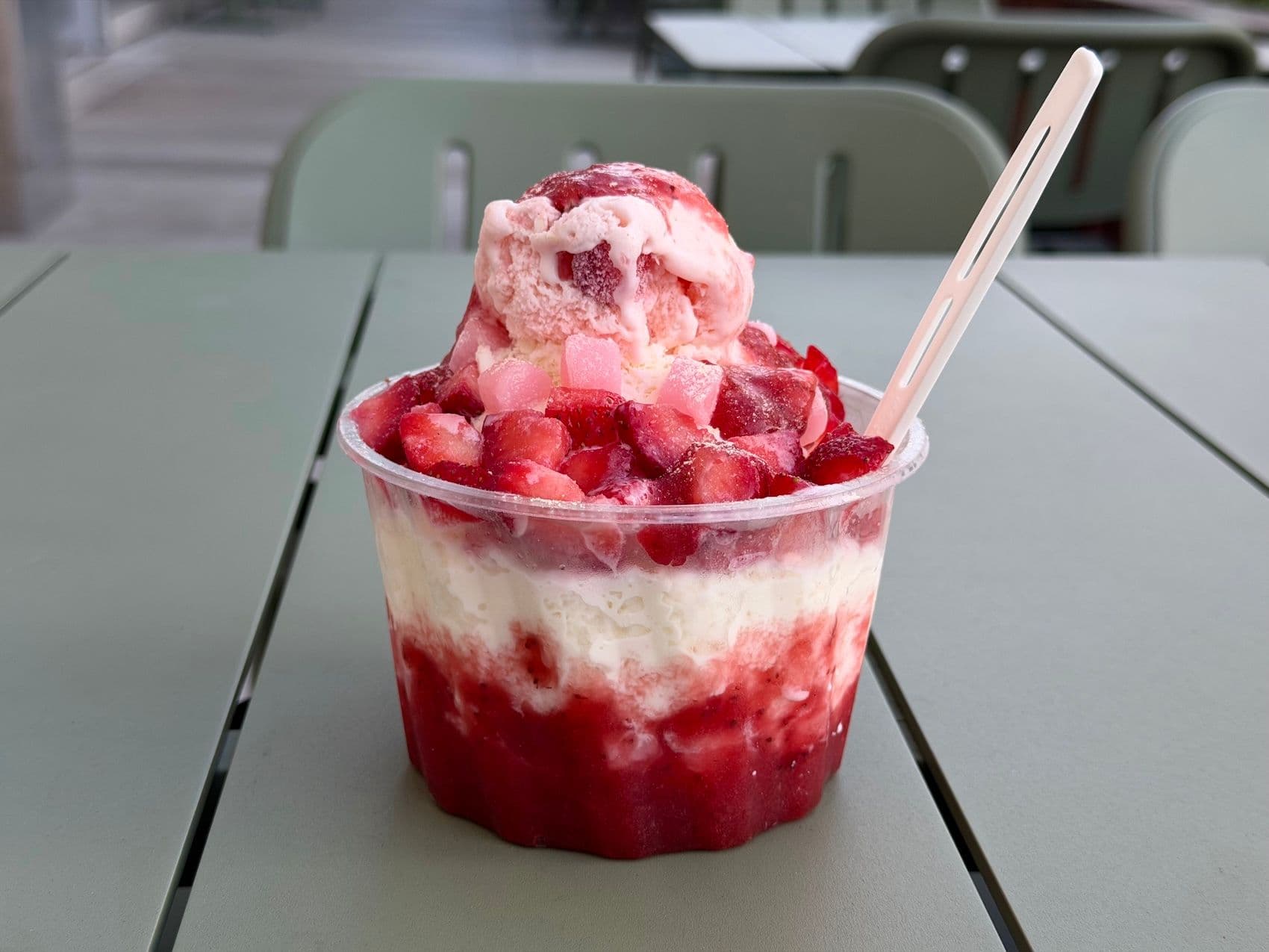 Strawberry bingsu on a blue table outside.