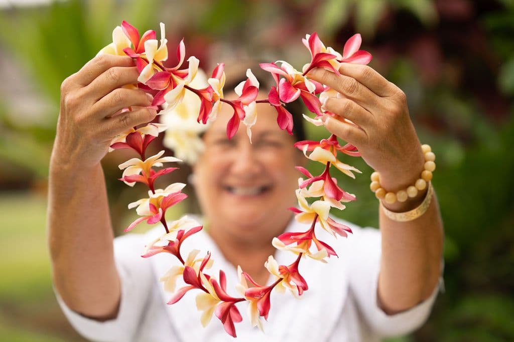 A woman holding up a lei.