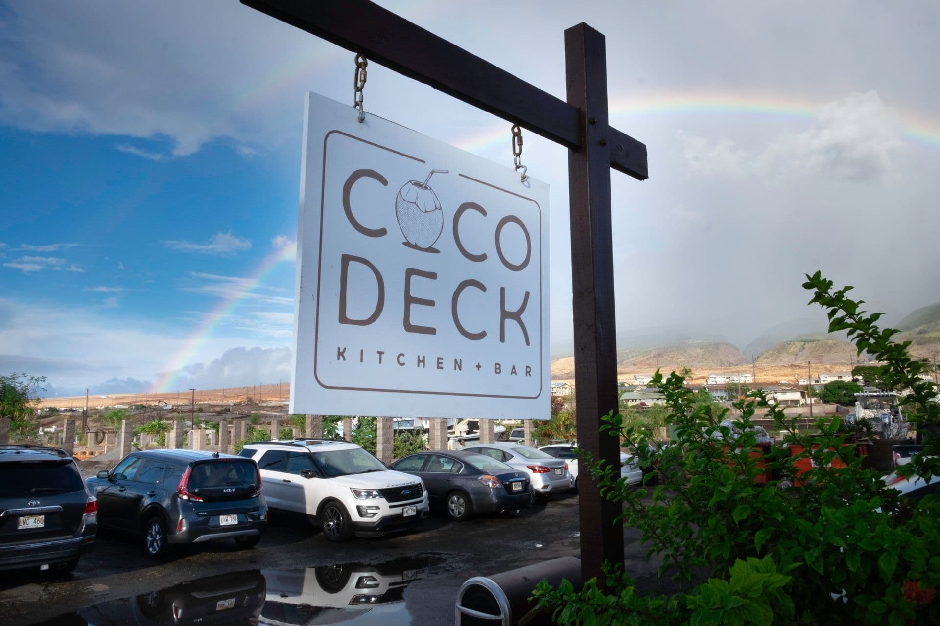 Coco Deck sign with double rainbow behind it