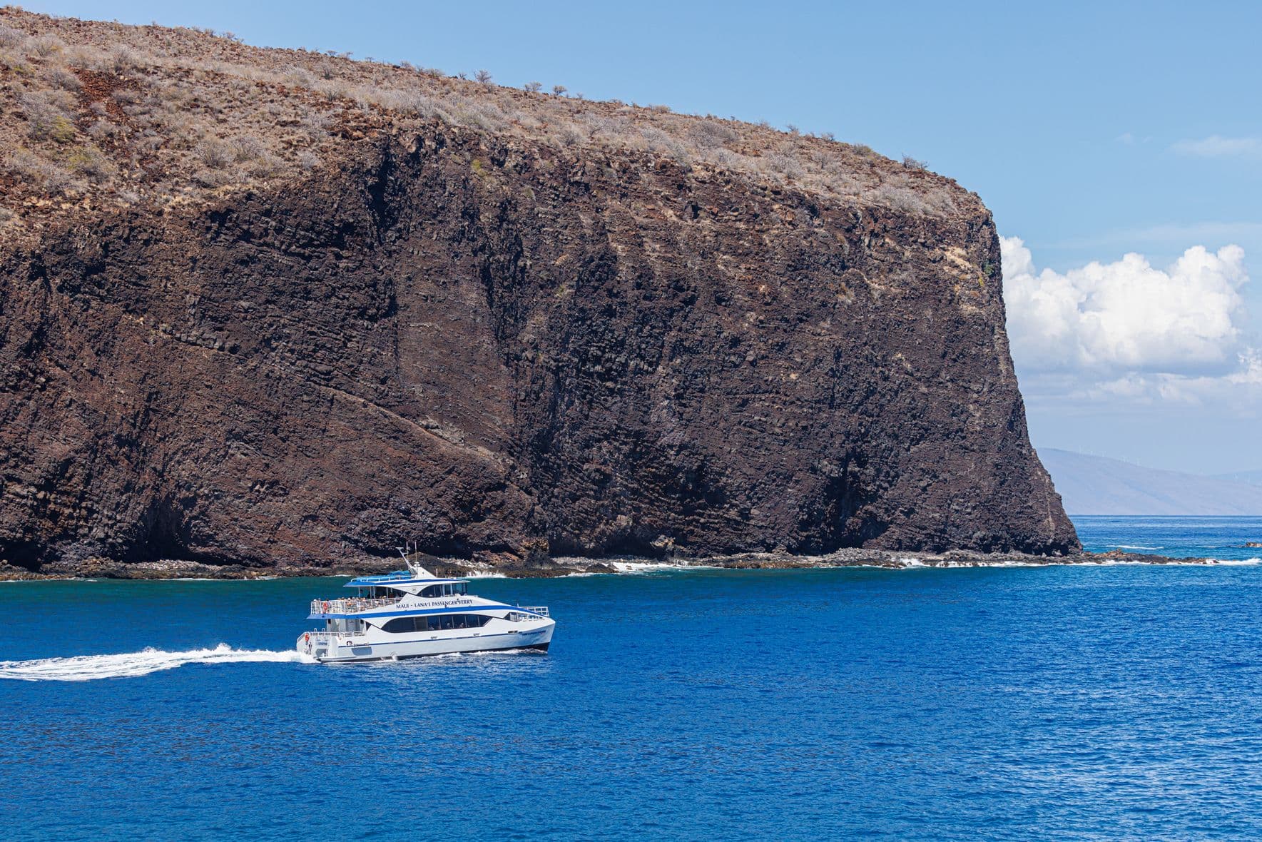 Ferry boat by a huge cliff coming out of the ocean