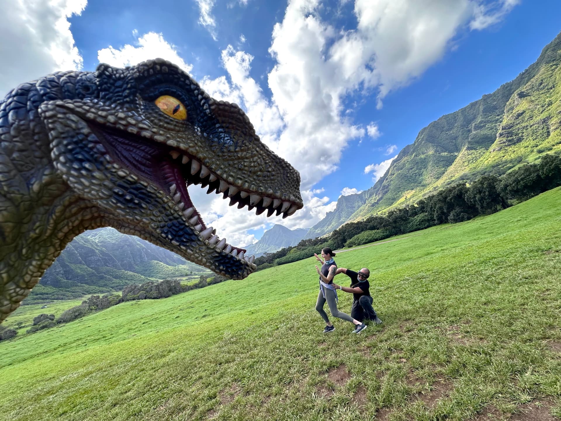 Two people being attacked by a CGI dinosaur at Kualoa Ranch.