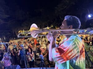 jazz musician playing trumpet in front of crowd at concert at night
